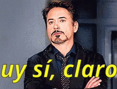 A Man In A Suit And Tie Is Standing With His Arms Crossed In Front Of A Sign That Says Uy Si Claro . GIF
