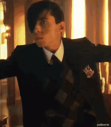A Man In A Suit And Tie Is Standing With His Arms Outstretched In A Room . GIF