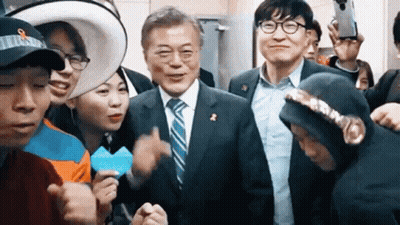 A Man In A Suit And Tie Is Surrounded By A Group Of People . GIF