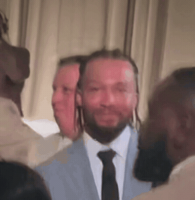 a man in a suit and tie is surrounded by other people