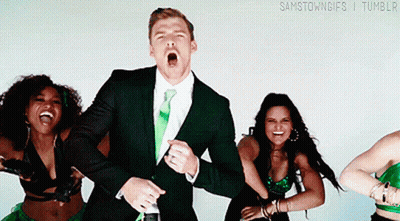 A Man In A Suit And Tie Is Surrounded By Women In Green Outfits GIF