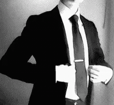 A Man In A Suit And Tie Is Taking Off His Jacket . GIF