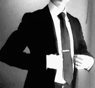 A Man In A Suit And Tie Is Taking Off His Jacket . GIF