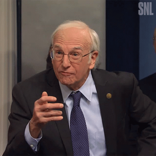 A Man In A Suit And Tie Is Talking In Front Of A Snl Logo GIF