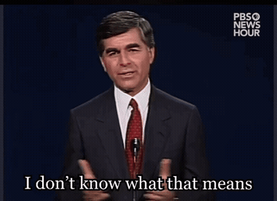 A Man In A Suit And Tie Is Talking Into A Microphone And Says I Don T Know What That Means GIF