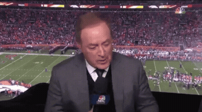 A Man In A Suit And Tie Is Talking Into A Microphone While Watching A Football Game On Nbc GIF