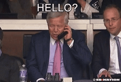 A Man In A Suit And Tie Is Talking On A Cell Phone While Another Man Says Hello GIF
