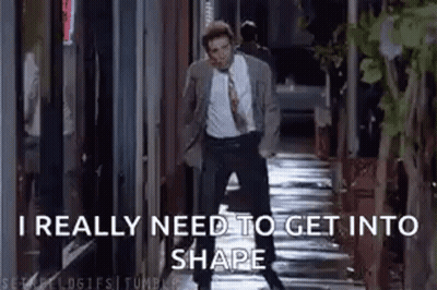A Man In A Suit And Tie Is Talking On A Cell Phone While Walking Down A Sidewalk . GIF