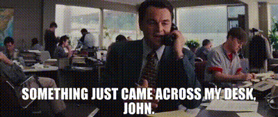 A Man In A Suit And Tie Is Talking On A Cell Phone With The Words Something Just Came Across My Desk John Below Him GIF