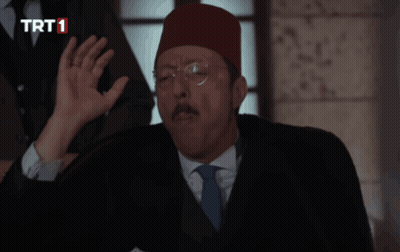 A Man In A Suit And Tie Is Talking On A Phone With A Trt1 Logo In The Corner GIF