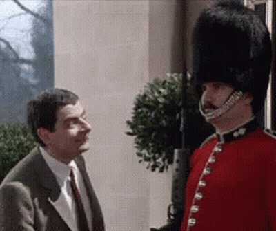 A Man In A Suit And Tie Is Talking To A Man In A Red Uniform With A Hat On . GIF
