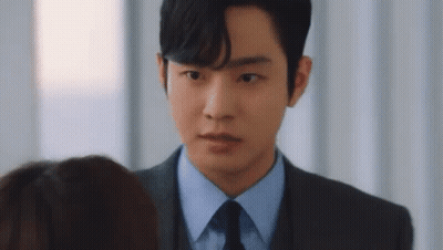 A Man In A Suit And Tie Is Talking To A Woman . GIF