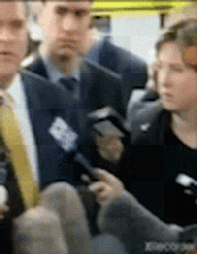 A Man In A Suit And Tie Is Talking To A Woman In A Black Dress . GIF
