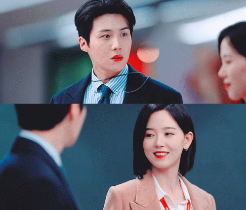 A Man In A Suit And Tie Is Talking To A Woman In A Tan Jacket GIF