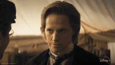 A Man In A Suit And Tie Is Talking To Another Man In A Disney + Advertisement GIF