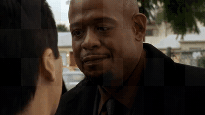 A Man In A Suit And Tie Is Talking To Another Man In A Park . GIF