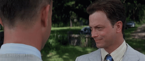 A Man In A Suit And Tie Is Talking To Another Man In A Park With The Words Kinodscura On The Bottom GIF