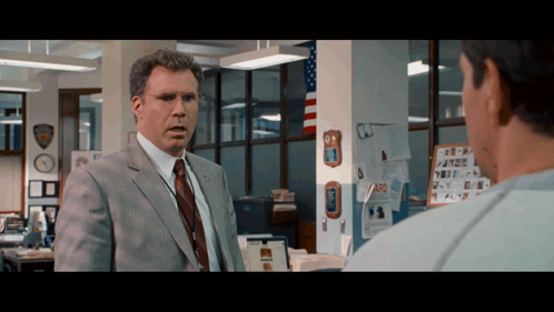 A Man In A Suit And Tie Is Talking To Another Man In A Police Station GIF