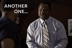 A Man In A Suit And Tie Is Talking To Another Man In A Room . GIF
