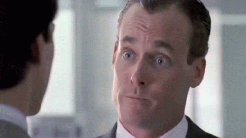 A Man In A Suit And Tie Is Talking To Another Man In A Room . GIF