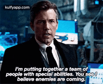 A Man In A Suit And Tie Is Talking To Another Man In A Room . GIF