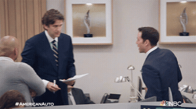 A Man In A Suit And Tie Is Talking To Another Man In An Office With Nbc Written On The Bottom Right GIF