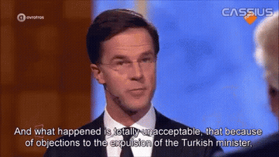 A Man In A Suit And Tie Is Talking To Another Man On A Tv Show GIF
