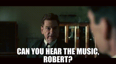 A Man In A Suit And Tie Is Talking To Another Man With The Words Can You Hear The Music Robert GIF