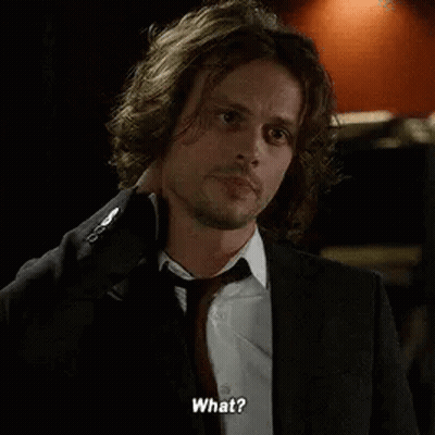 A Man In A Suit And Tie Is Talking To Someone While Holding His Neck . GIF