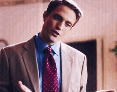 A Man In A Suit And Tie Is Talking To Someone While Standing In A Room . GIF