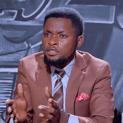 A Man In A Suit And Tie Is Talking With His Hands Outstretched GIF