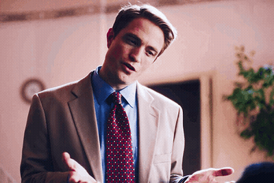 a man in a suit and tie is talking with his hands outstretched