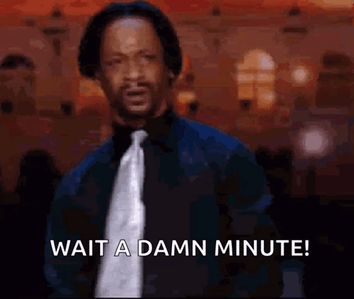 A Man In A Suit And Tie Is Waiting For A Damn Minute . GIF