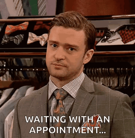 A Man In A Suit And Tie Is Waiting With An Appointment In A Store . GIF