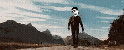 A Man In A Suit And Tie Is Walking Down A Dirt Road . GIF