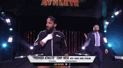 A Man In A Suit And Tie Is Walking Down A Wrestling Ring With A Man In A Suit Behind Him . GIF