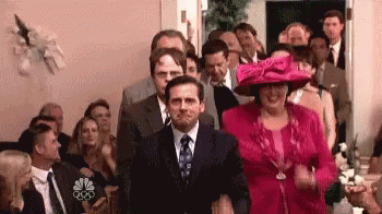 A Man In A Suit And Tie Is Walking Down The Aisle Of A Wedding Ceremony . GIF