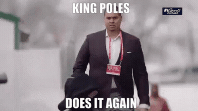 A Man In A Suit And Tie Is Walking Down The Street With A Hat On His Shoulder . GIF