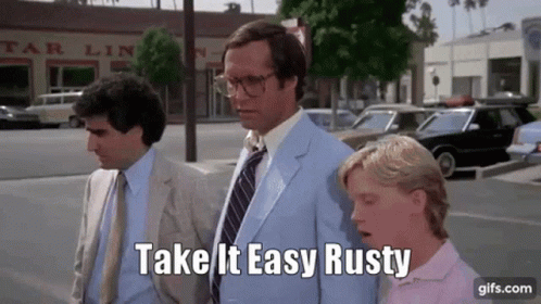 A Man In A Suit And Tie Is Walking Down The Street With Two Other Men And Says `` Take It Easy Rusty '' . GIF