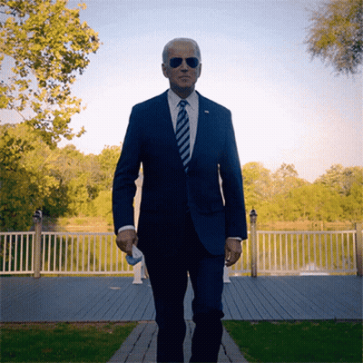 A Man In A Suit And Tie Is Walking On A Path GIF