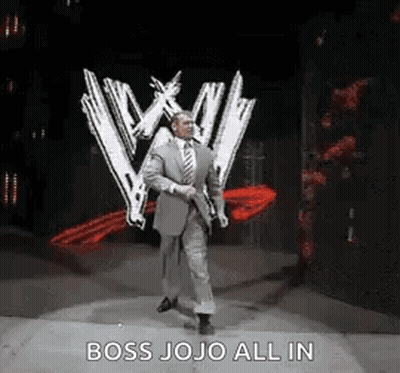 A Man In A Suit And Tie Is Walking On A Stage In Front Of A W Logo . GIF