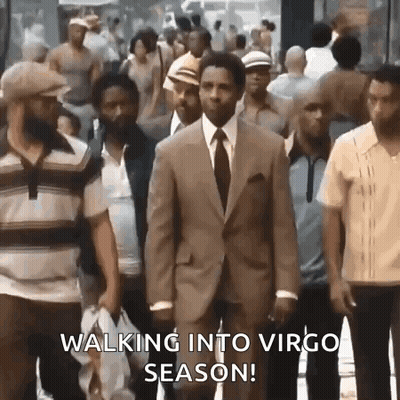 A Man In A Suit And Tie Is Walking Through A Crowd Of People On A City Street . GIF
