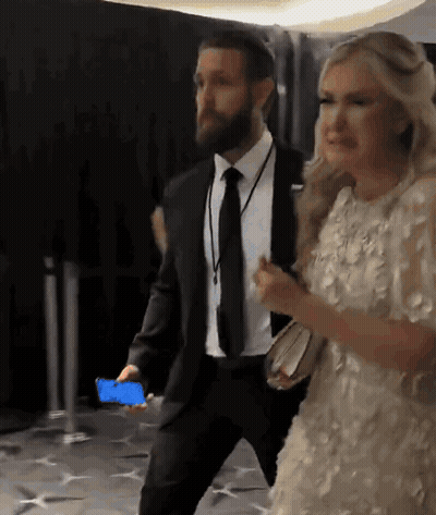 A Man In A Suit And Tie Is Walking With A Woman In A Dress GIF