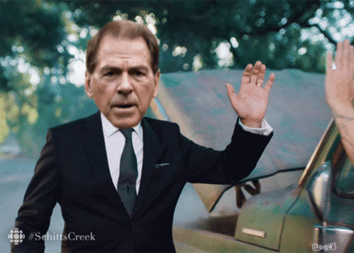 A Man In A Suit And Tie Is Waving His Hand GIF