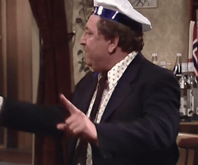 A Man In A Suit And Tie Is Wearing A Captain 'S Hat GIF