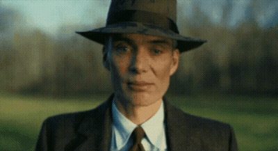 A Man In A Suit And Tie Is Wearing A Fedora Hat . GIF