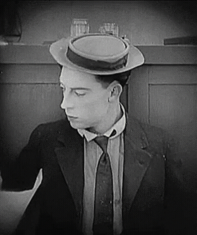 A Man In A Suit And Tie Is Wearing A Hat And A Tie . GIF