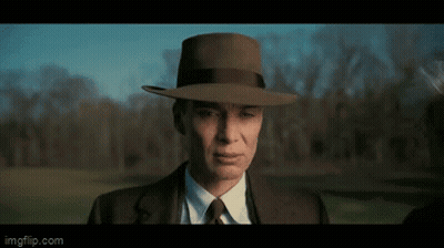 A Man In A Suit And Tie Is Wearing A Hat . GIF