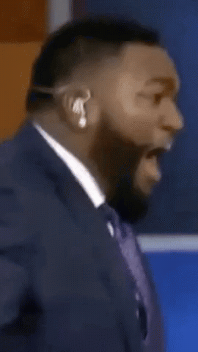 A Man In A Suit And Tie Is Wearing A Headset And Making A Funny Face GIF