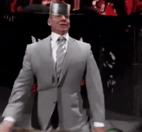 A Man In A Suit And Tie Is Wearing A Knight 'S Hat . GIF